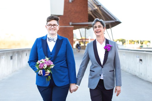 photo of two people holding hands and walking in blue and gray suits